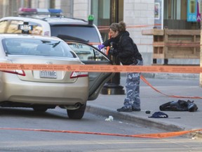 A Montreal police officer takes photographs of a taxi cab during an investigation of a shooting outside Muzique Audio Bar on St Laurent Boulevard near Roy in Montreal, Monday April 25, 2016.