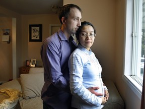 Jason Lizotte, left, with his pregnant wife Jackie (Liang) Zhong in their home on  April 27, 2016. Using his discretionary powers, Quebec's Health Minister Gaétan Barrette 
demanded that the province's health insurance board issue Zhong a temporary medical card.