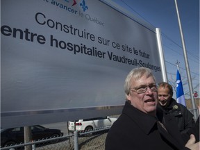 Quebec Health Minister Gaétan Barrette stands in front of the sign announcing a planned new hospital in the Vaudreuil-Soulanges region.