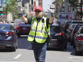A Montreal police sergeant directs traffic and pedestrians at the corner of Peel and Ste. Catherine Sts. in Montreal Monday, July 20, 2015.