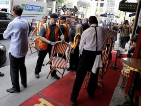 Alain Creton, left, owner of Chez Alexandre, watches as city workers return his chairs after attempting to seize them in Montreal on Thursday May 12, 2016. The city and the brasserie are in a dispute over where the terrasse should be installed.