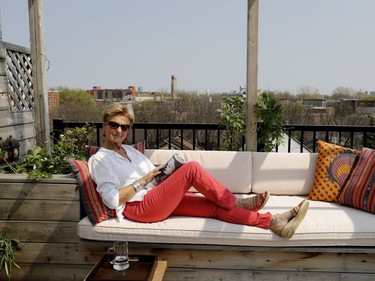 Lies Ouwerkerk reads on the rooftop balcony of her home. The tower of the Atwater Market is seen in the distance. (Allen McInnis / MONTREAL GAZETTE)