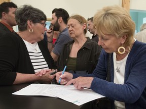 Trish Kelly, right, signs up to join a committee to help beautify the town of Hudson as pro-mayor Barbara Robinson, left, speaks to another resident after a public meeting held by the town to explain how they will roll out the municipality's strategic plan on Thursday, May 12, 2016. (Peter McCabe / MONTREAL GAZETTE)