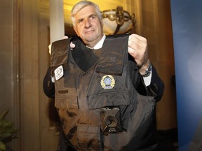 Richard Lafond, in charge of special projects for the Montreal police department, holds a police officer's vest with a body camera during a press conference at  Montreal city hall on May 18, 2016. The city of Montreal and Montreal police (SPVM) have launched a pilot project in which about 30 officers will initially wear body cameras to monitor their interactions. It is a first in Quebec.