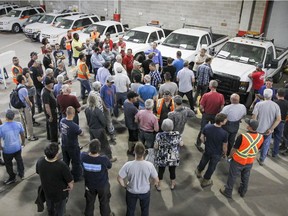 Buyers gather around auctioneer Jean-François Lajeunesse during an auction of goods at the St-Laurent borough municipal yards in Montreal Wednesday May 25, 2016.