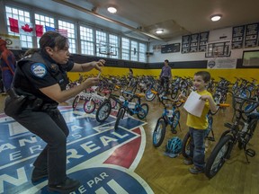 Montreal Police officer Anna Pallotta takes a photo of 5-year-old Danny Larose on his new bicycle he received from Sun Youth in Montreal Wednesday May 25, 2016.