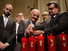 Montreal mayor Denis Coderre helps Eric Bissel light one of six candles during a Holocaust commemorative ceremony to mark Yom HaShoah, Holocaust Remembrance Day, at Montreal city hall on Wednesday May 4, 2016. Bissel and his family managed to escape Europe to the Dominican Republic in 1942 avoiding capture by the Nazis. His family came to Canada in 1948.