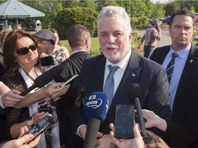 Quebec Premier Philippe Couillard responds to reporters' questions as he arrives at a special party caucus meeting on Monday.