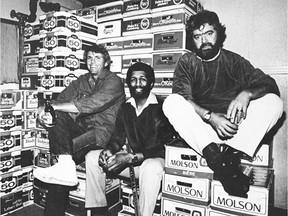 Expos pitcher Bill Lee (left) and Montreal Gazette editorial cartoonist Terry Mosher (right) pose on top of beer cases in the  basement of the Cul de Sac bar with bar co-owner Duke Earl in the early 1980s.