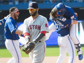 Toronto Blue Jays third baseman Josh Donaldson (20) and Toronto Blue Jays catcher Russell Martin (55) rush Toronto Blue Jays second baseman Devon Travis, back right, after travis hit the game-winning RBI, which Marin scored on, as Boston Red Sox second baseman Dustin Pedroia (15) looks on during ninth inning AL baseball action in Toronto on Saturday, May 28, 2016.