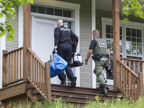 Police officers enter a house in Val Morin,l where Laval police say a meth lab was discovered, Wednesday, June 8, 2016.