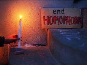 A candle shines near a sign at a vigil in Seattle for the victims of a mass shooting at Pulse nightclub in Orlando, Fla.