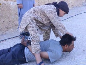 A screen grab image from video shows an ISIS soldier beheading a Syrian prisoner.
