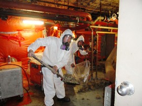 Workers remove asbestos from the furnace room of a Montreal apartment building. The fibrous mineral was widely used in homes and other buildings across Canada in the 20th century.