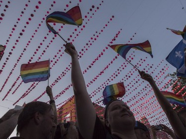 Demonstrators wave rainbow flags during a vigil for the victims of the shooting in Orlando Thursday, June 16, 2016 in Montreal.