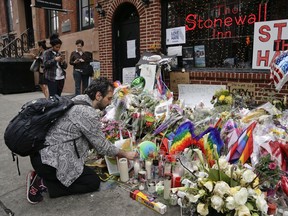 In this June 16, 2016 file photo, a man lights candles on a memorial outside the Stonewall Inn for victims of the Orlando Shooting, in New York. President Barack Obama is designating the Stonewall Inn in New York a national monument, the first to honour gay rights.