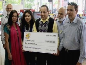 This June 2012 file photo provided by WMAQ-TV in Chicago, shows Urooj Khan, center, holding a ceremonial check in Chicago for $1 million as winner of an Illinois instant lottery game. At left, is Khan's wife, Shabana Ansari. Khan died suddenly on July 20, 2012, just days before he was to collect his winnings. With his departure from office this week, Stephen Cina, the former Cook County medical examiner leaves behind a beguiling mystery that he set in motion with a sensational declaration three years ago that Khan was poisoned with cyanide. () ORG XMIT: CX102