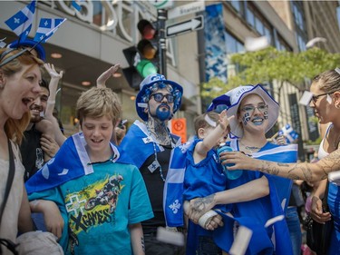 Tanya Normandeau, second from right, and Luc Allain-Rousselle, centre, along with their one year-old son Jack Allain-Rousselle watch the annual Fete Nationale parade for Saint-Jean-Baptiste day on Ste. Catherine street in downtown Montreal on Friday,