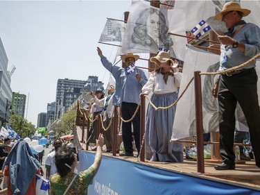 A float with people in traditional dress take part in the annual Fete Nationale parade for Saint-Jean-Baptiste day on Ste. Catherine Street