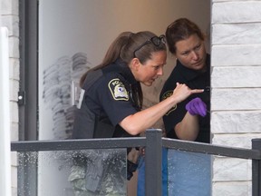 Laval police dust for prints at the entrance of an apartment on Levesque Blvd. in Laval June 29, 2016, following an overnight homicide. A man was found dead at the foot of stairs inside the building.