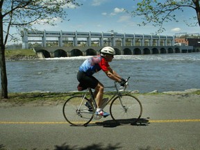 A cyclist tours along the 2.5-kilometre-long shoreline of of Île de la visitation nature park near a hydro-electric dam on Rivière des Prairies.