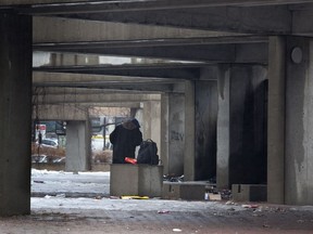 A man takes shelter from the rain at Viger square, where many homeless people camp, in Montreal, Tuesday April 8, 2014.