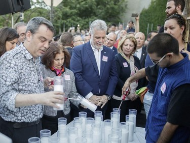The man on the right moments before he attempted an assault on Quebec Premier Philippe Couillard, seen in the centre, lights a candle during a vigil at Parc de l'Espoir in Montreal to honour the victims of the June 11/12 shooting attack at the gay nightclub Pulse in Orlando, Florida, on Thursday, June 16, 2016.