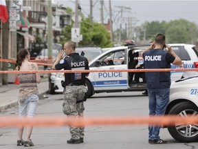 An SPVM police officer speaks with a woman at the scene where a man in his 70s was shot inside the Hillside Cafe near the corner of Fleury and André Jobin streets in Montreal on Thursday, June 2, 2016.