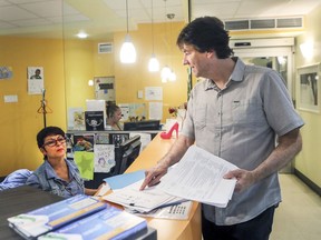 Stéphane Defoy, right, community organizer at Clinique communautaire de Pointe-Saint-Charles speaks to Sylvie Laplante at the front desk of the clinic on June 2, 2016. This community clinic is seeking a class action against the Quebec government and private clinics over what it considers are illegal fees charged to patients.
