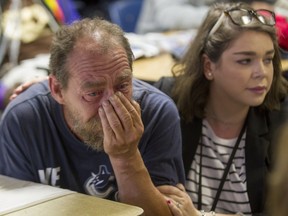 Yves Brazeau, left, is comforted by crisis worker Lisa Marie Scolack during a service of remembrance at the Saint Michael's Mission on President Kennedy in downtown Montreal, Thursday June 23, 2016, for the 14 clients of the Mission who've died in the last year. Kim Gloade, a client who died in February, was Brazeau's girlfriend.