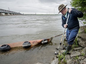 Daniel Green uses a rod to move rocks in the water at the bank of the St. Lawrence River, beside the Bonaventure Expressway, just west of the Victoria bridge in Montreal, on Thursday, June 9, 2016.