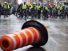 Montreal police are brought to a halt for a moment after anti-capitalists threw construction cones across Ste-Catherine street as they marched through the streets of Montreal during May Day protests in Montreal on Sunday May 1, 2016.
