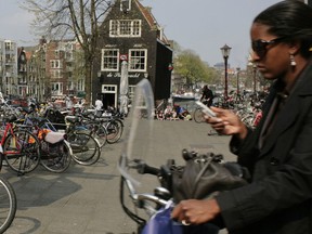 An issue in many cities: A woman on a bicycle uses her cellphone as she rides past a city map in Amsterdam, Netherlands. The Dutch government said last week it is considering banning the country's millions of cyclists from using their cellphones while riding, saying pedaling and phones are a dangerous mix.
