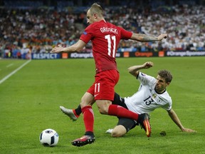 Poland's Kamil Grosicki, left, is tackled by Germany's Thomas Mueller during the Euro 2016 Group C soccer match between Germany and Poland at the Stade de France in Saint-Denis, north of Paris, France, Thursday, June 16, 2016.