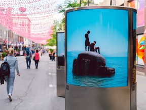 A lightbox displays a photo by Alicja Dobrucka in the Aires Libres public art exhibition along Ste-Catherine St. E. This image is from her series Concrete Mushrooms, about bunkers built by the Albanian government in the 1980s that are now either abandoned or put to new uses.