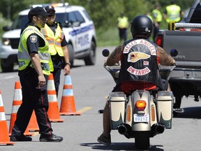 A member of the Hells Angels stops at a police roadblock near the Hells Angels Nomads compound before the group's Canada Run event in Carlsbad Springs, Ont., near Ottawa, on Friday, July 22, 2016.