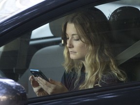 A driver uses her mobile phone while sitting in traffic Wednesday, June 22, 2016, in Sacramento, Calif. Quebec motorists face fines of between $80 and $100 and four demerit points for handling a phone in any way while driving, even when stuck in traffic or stopped at a traffic light.