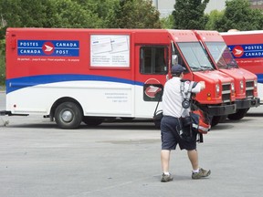A postal worker walks past Canada Post trucks at a sorting centre in Montreal, Friday, July 8, 2016. The Canadian Union of Postal workers has called for a 30-day truce to negotiate a new contract and avoid a strike or lockout.