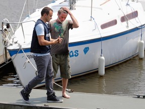 An investigator with Montreal police, left, speaks with a boater at the Beaconsfield Yacht Club ion Wednesday July 20, during a search for the body of Pierre Lajeunesse, who fell overboard into Lac Saint-Louis Tuesday.