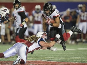 Ottawa Redblacks running back Kienan Lafrance, right, leaps to avoid a tackle by Montreal Alouettes linebacker Bear Woods during fourth quarter CFL football action, in Montreal on Thursday, June 30, 2016.