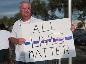 Hal Lacey holds an "All Lives Matter" sign in support of police officers during a Black Lives Matter rally at the corner of State Highway 77 and 23rd Street on Sunday, July 10, 2016, in Panama City, Fla.