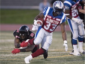 Montreal Alouettes running back Brandon Rutley (33) carries the ball as Ottawa Redblacks linebacker David Hinds (20) grabs his foot during second quarter of a CFL exhibition game Saturday, June 13, 2015 in Quebec City.