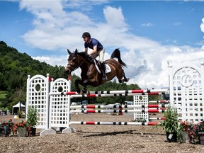Mario Deslauriers and his horse jump over an obstacle at the Bromont Equestrian Olympic Park in Bromont, Quebec, on Aug. 4, 2015.