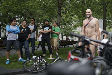 Tourists watch as people gather for the World Naked Bike Ride at Dorchester Square in Montreal on Saturday, July 16, 2016. The World Naked Bike Ride event aims to encourage cycling, promote environmentalism, and address body image issues.