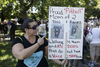 Tina Daddio, owner of two pit bull dogs, shows her sign as she gathers along with other dog owners at Pelican Park to take part in a protest against breed-specific legislation for dogs in Montreal on Saturday, July 16, 2016. The demonstration was against the recent proposed bans on pit bull dogs in Quebec after a series of high profile attacks.