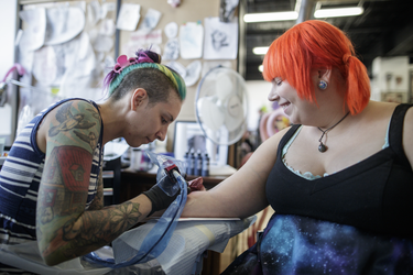 Ashley Gagnon, right, gets a tattoo of the character Vulpix from tattoo artist Josi Labelle as part of a Pokemon Go promotion day at DFA Tattoos in Montreal on Sunday, July 24, 2016.