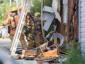 Montreal firefighters rip off the side of a building while fighting a fire at a house in Notre Dame Street East at 4th Avenue in Pointe-six-trembles, Montreal, Thursday July 14, 2016. Police suspect arson.