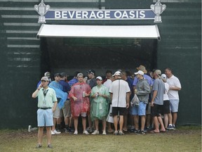 Fans take cover at the 18th green during a weather delay in the third round of the PGA Championship golf tournament at Baltusrol Golf Club in Springfield, N.J., Saturday, July 30, 2016.