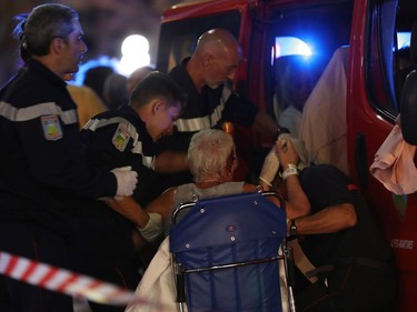EDITORS NOTE: Graphic content / Rescue workers help an injured woman to get in a ambulance on July 15, 2016, after a truck drove into a crowd watching a fireworks display in the French Riviera town of Nice. A truck ploughed into a crowd in the French resort of Nice on July 14, leaving at least 60 dead and scores injured in an "attack" after a Bastille Day fireworks display, prosecutors said on July 15.