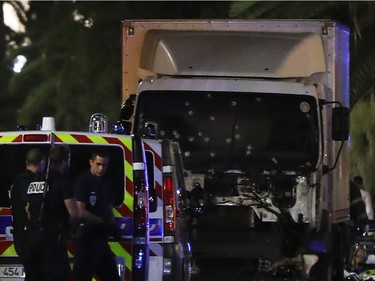 Police officers stand near a van, with its windscreen riddled with bullets, that ploughed into a crowd leaving a fireworks display in the French Riviera town of Nice on July 14, 2016. Up to 30 people are feared dead and over 100 others were injured after a van drove into a crowd watching Bastille Day fireworks in the French resort of Nice on July 14, a local official told French television, describing it as a "major criminal attack".